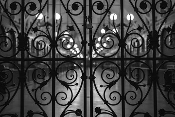 Black and white, bw, Beautiful closed wrought-iron gates, evening, night, light of lanterns. Central Market Square Krakow, Poland