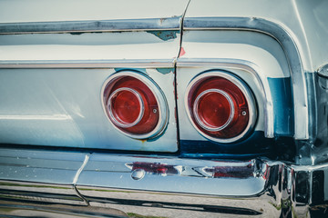 Detail, rear lights and decoration of an old, rusty american car from the 60's.