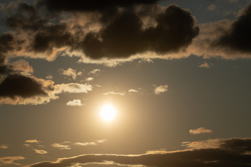 Fototapeta na wymiar bright sun in an orange sky with dark clouds at sunset