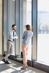 Business colleagues standing talking while leaning in office window