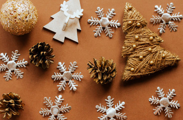  golden christmas toys, silver snowflakes and cones on a brown background