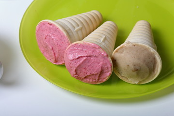 Homemade strawberry and banana ice cream. In edible horns on a plate.