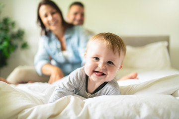 Fototapeta premium happy family mother, father and son at home in bed