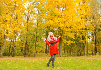 Obraz premium young pretty plus size caucasian blonde woman in red wool coat walks in autumn park