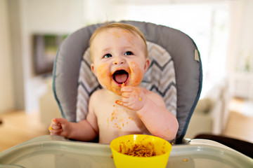 A Little baby eating her dinner and making a mess
