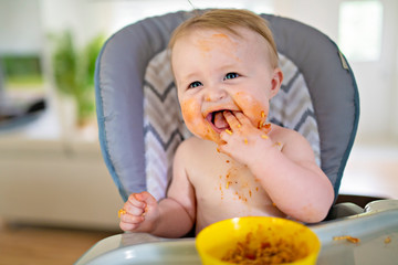 A Little baby eating her dinner and making a mess