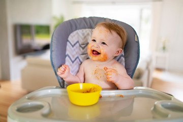 A Little baby eating her dinner and making a mess