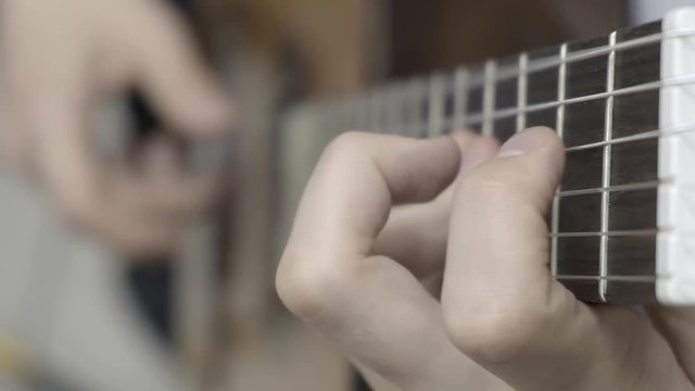 Close up of left hand playing guitar. Slow mo