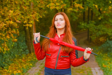 young pretty plus size caucasian woman walks with red umbrella in autumn park