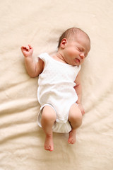 Cute newborn child is sleeping on a blanket.