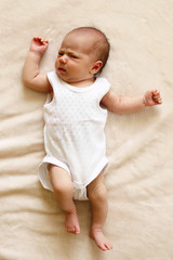 Cute newborn child is lying on a blanket and looking into the camera.