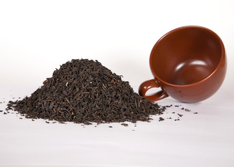 A heap of Chinese black loose leaf tea with brown cup
