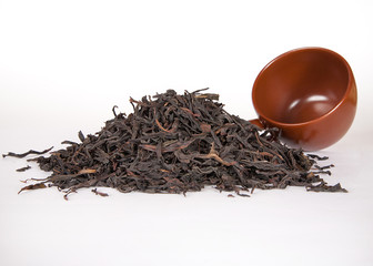 A heap of Chinese black loose leaf tea with brown cup