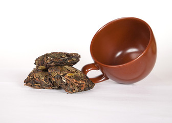 A heap of Chinese black loose leaf tea with brown cup