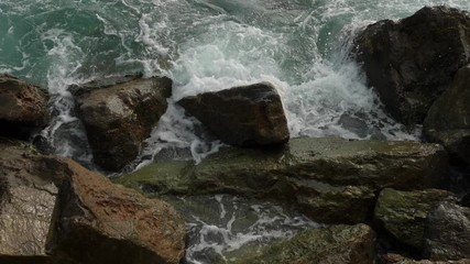 Sea waves crashing on stone beach.