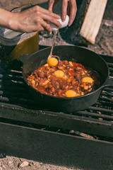 Making breakfast with eggs in cast iron skillet on the camp site. 