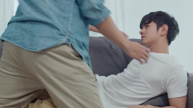 Young Asian Gay couple hug and kiss at home. Attractive Asian LGBTQ pride men happy relax spend romantic time together while lying sofa in living room concept. Slow motion Shot.