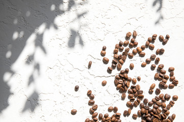 Lots of coffee beans loose on a white textured background. The concept of good morning.