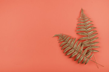 Golden palm leaves on coral background. Summer background with golden tropical leaves, copy space