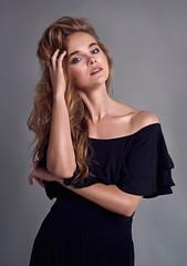 Fototapeta premium Young attractive women model ,long hair, wearing black suit, posing in studio.Grey background.