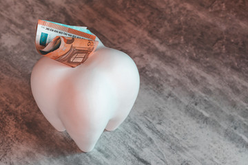 big tooth in the form of a piggy bank. it has the euro. paid dentistry.
