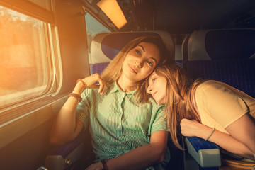 Two women Friends looking at sunset while traveling by train. Candid authentic moment