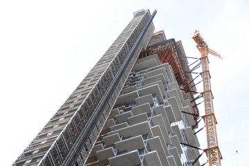 LOW ANGLE VIEW OF CRANE NEXT TO SKYSCRAPER AGAINST CLEAR SKY