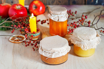 Jar of jam and jar of honey among autumn fruits and plants.
