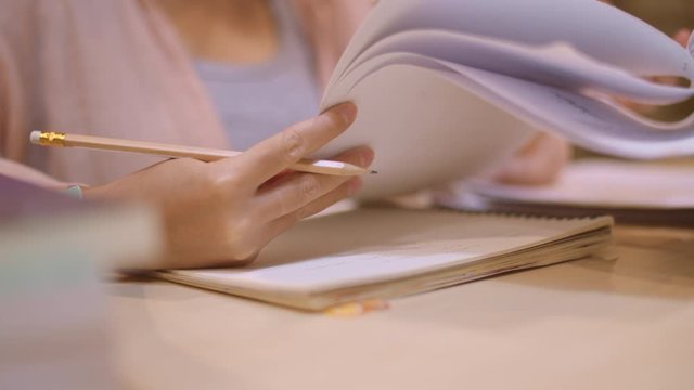 Asian student women reading books in library at university. Young undergraduate girl do homework, read textbook, study hard for knowledge on lecture desk at college campus overtime night. Slow motion.
