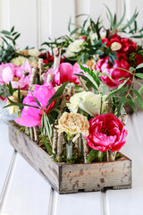 Floral decoration with peonies, carnations and roses inside the wooden box