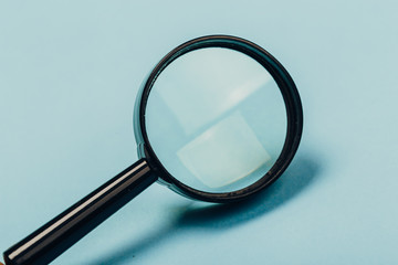 Small magnifying glass on pastel blue background