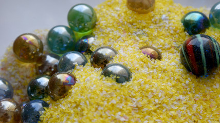 bright background beautiful colorful glass balls in yellow with pink and white sand