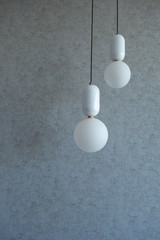 The structure of concrete is gray. Creative vintage background. Structural plaster. Modern lights in the form of a white ball on a long wire.