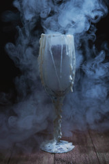 Glass decorated with streaks of wax in the clouds of white smoke and fog. Stylized drinks for Halloween