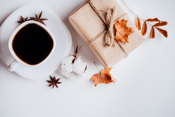 Autumn seasonal sale, black friday and online shopping concept. Cup of coffee and gift box decorated with dried foliage on white background. Flat lay, top view, copy space