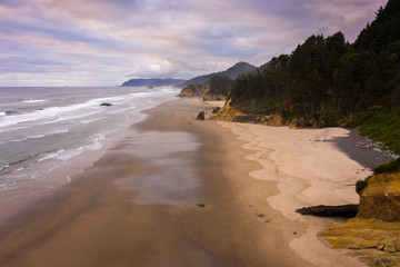 Sunrise View of Cannon Beach, Oregon. Beautiful morning light illuminates the white sand beaches and the Pacific Ocean along the stunning Oregon coastline during the summer season. 