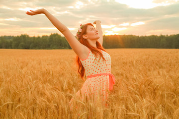 girl in polka dot dress walking in golden ripe wheat field at sunrise alone and enjoy the freedom