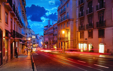 Porto, Portugal. Nighttime city life. Old town street with evening illumination and sky with clouds blue hour. Car speed lights on the road with asphalt.