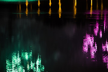 Beautiful fireworks over the city with reflection in the water, closeup and bokeh, blur effect, green