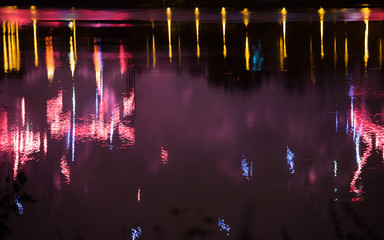 Beautiful fireworks over the city with reflection in the water, closeup and bokeh, blur effect, purple