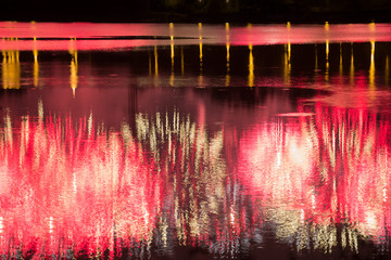 Beautiful fireworks over the city with reflection in the water, closeup and bokeh, blur effect, red