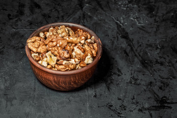 Wooden bowl with mixed nuts on dark background. Healthy food and snack