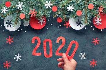 Hand holding number 2020, Christmas background with fir twigs