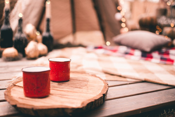 Hot coffee in red mugs outdoors at camping. Autumn season concept.