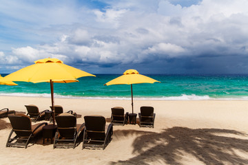 Sun umbrella and beach beds under the palm trees on tropical beach. Summer vacantion concept.