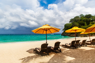 Sun umbrella and beach beds under the palm trees on tropical beach. Summer vacantion concept.