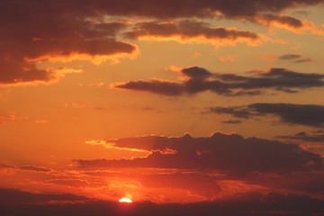 Beautiful fiery orange sunset background over the city, brown clouds in the sky at sunset