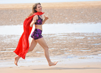 pretty girl on the beach with super hero cape