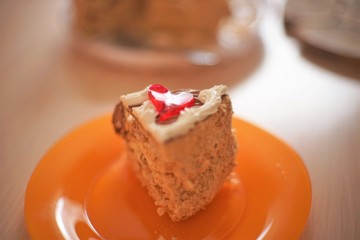 A piece of Kiev cake on an orange plate with a fork