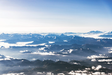 Obraz na płótnie Canvas Landscape aerial view of colorful blue Alps mountains with clouds and fog above Switzerland